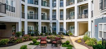 a courtyard with benches and plants in front of a building at The Flats at Summit Station, South Park, Pennsylvania